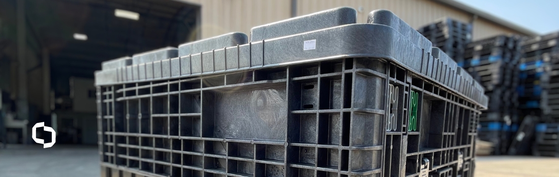 Close-up view of a black plastic container with a secure lid, stacked in an industrial yard, demonstrating the use of container lids for safe storage and transport in bulk material handling.