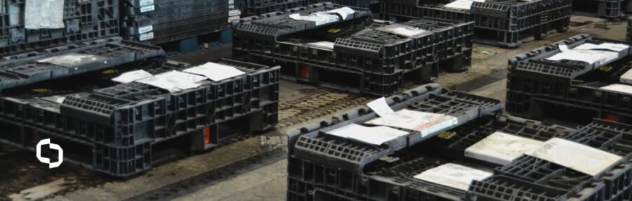 Several black bulk collapsible containers are laid out on the ground in a warehouse, ready for processing or recycling and highlighting their versatility in the supply chain.