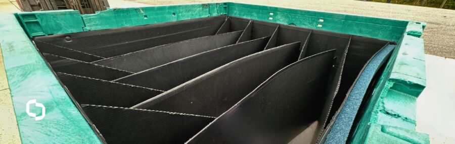 Custom dunnage solution with black plastic dividers inside a green industrial container, designed for maximum product protection during transport and handling.