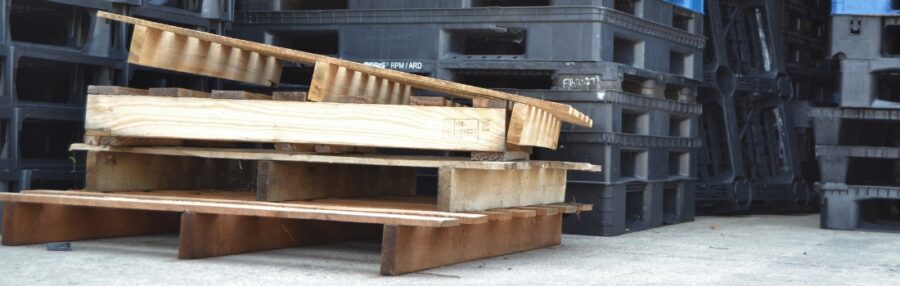 Stack of wooden pallets in a warehouse, illustrating the hidden costs of wood pallet breakage, mold, and maintenance challenges in supply chains