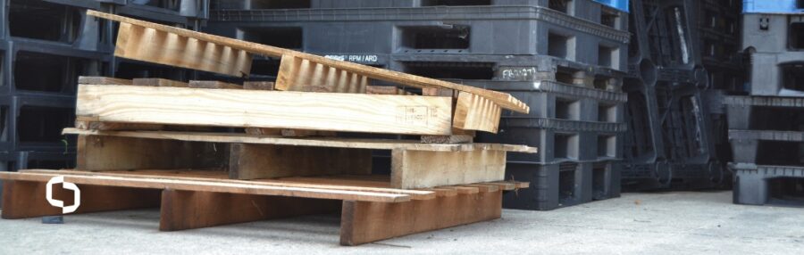 Stack of wooden pallets in a warehouse, illustrating the hidden costs of wood pallet breakage, mold, and maintenance challenges in supply chains